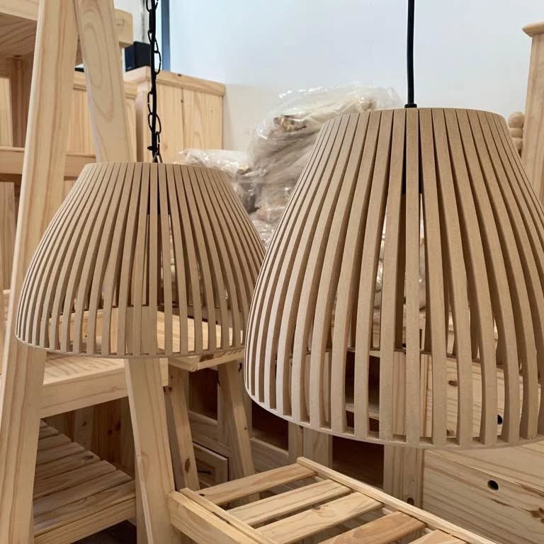 Dos lámparas colgantes de madera de color claro, colocadas en una habitación con otros muebles de madera.