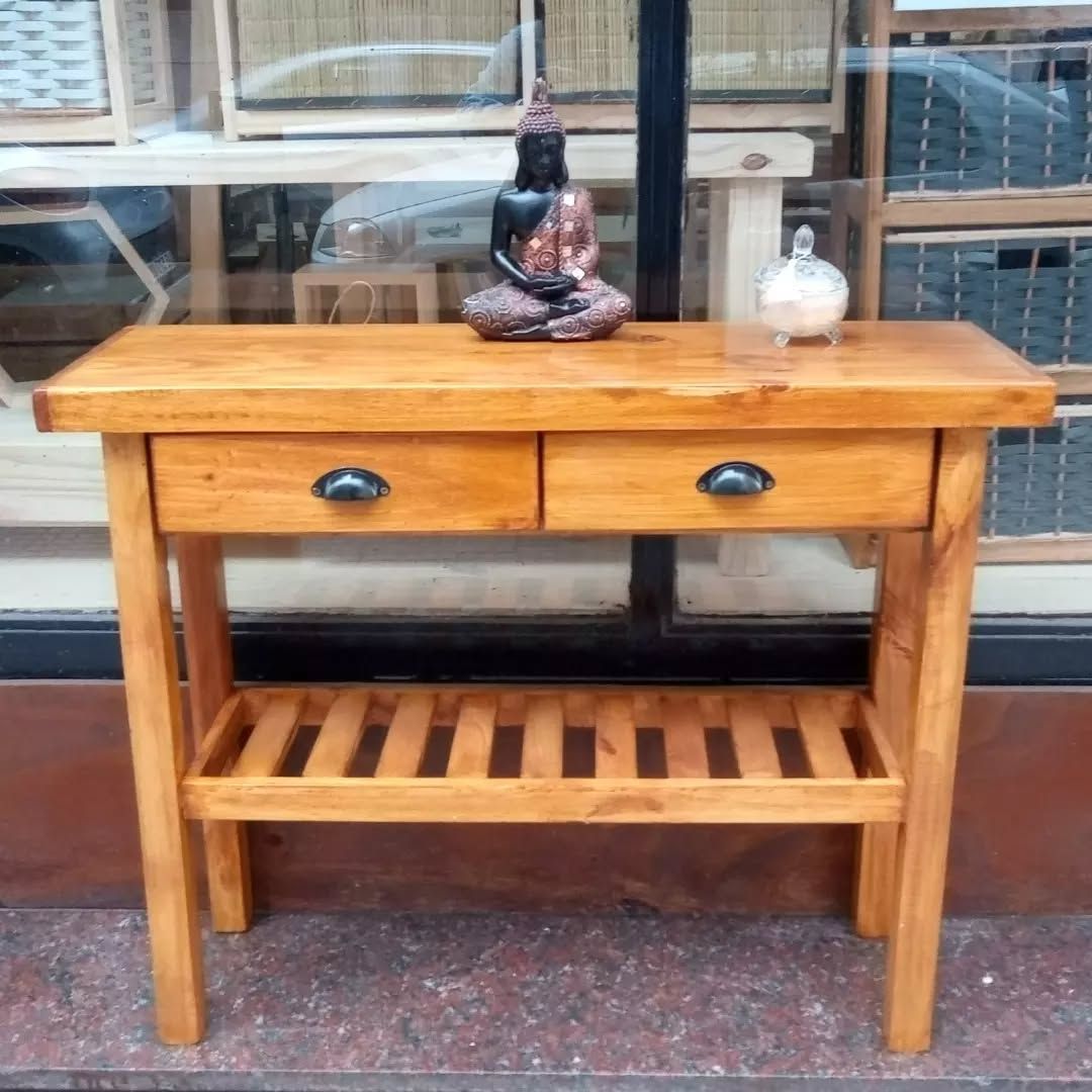 Consola de madera con dos cajones, estante inferior y elementos decorativos en la parte superior.