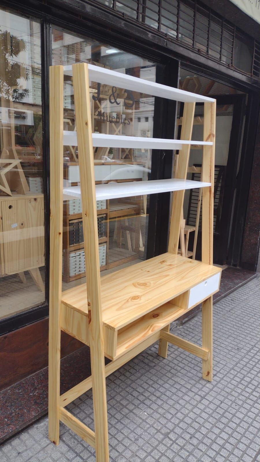 Escritorio de madera con estantes, que contiene libros, una planta, un osito de peluche y un cartel iluminado que dice 