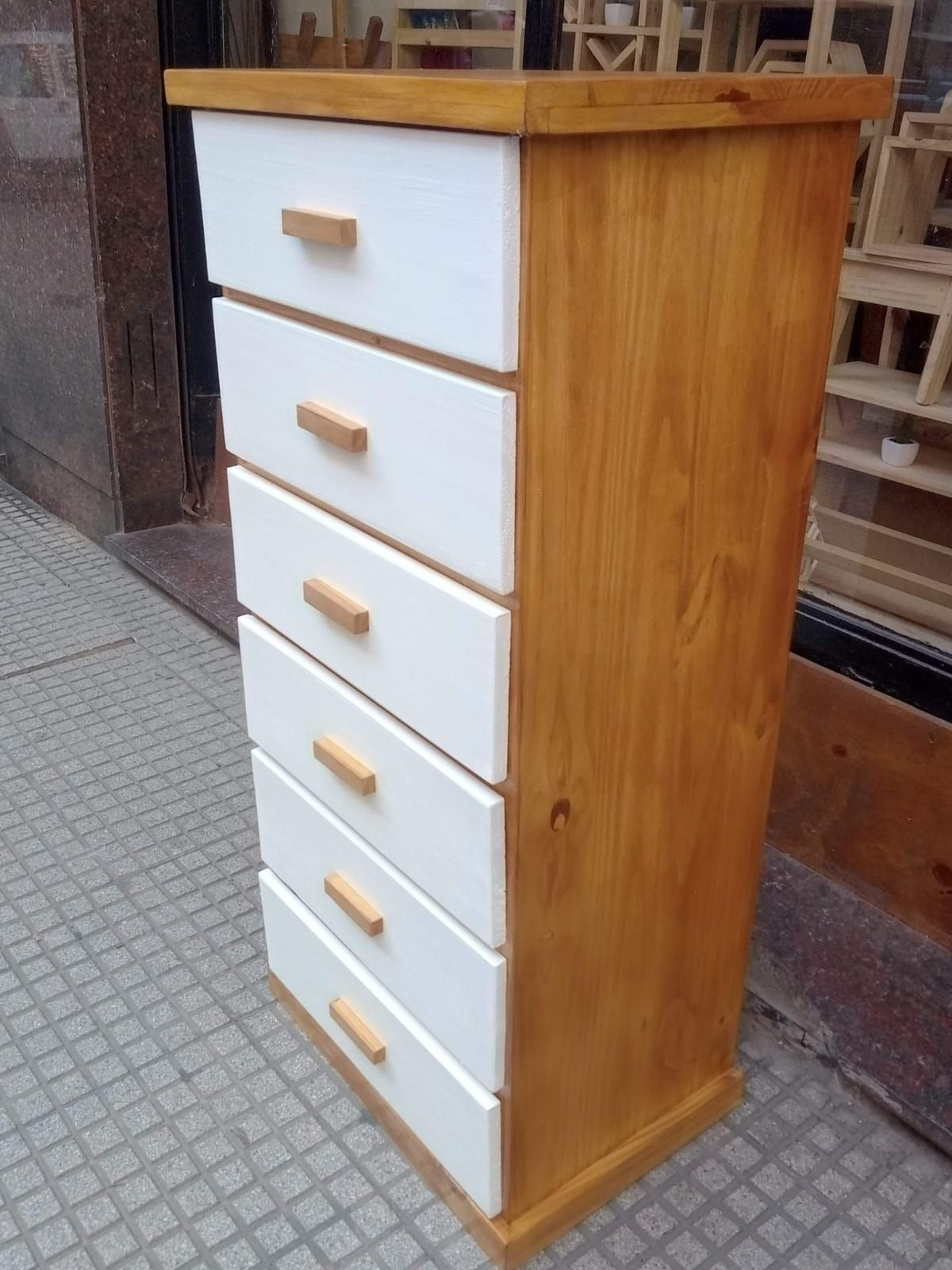 Cómoda alta de madera con seis cajones blancos y estructura y tiradores de madera.