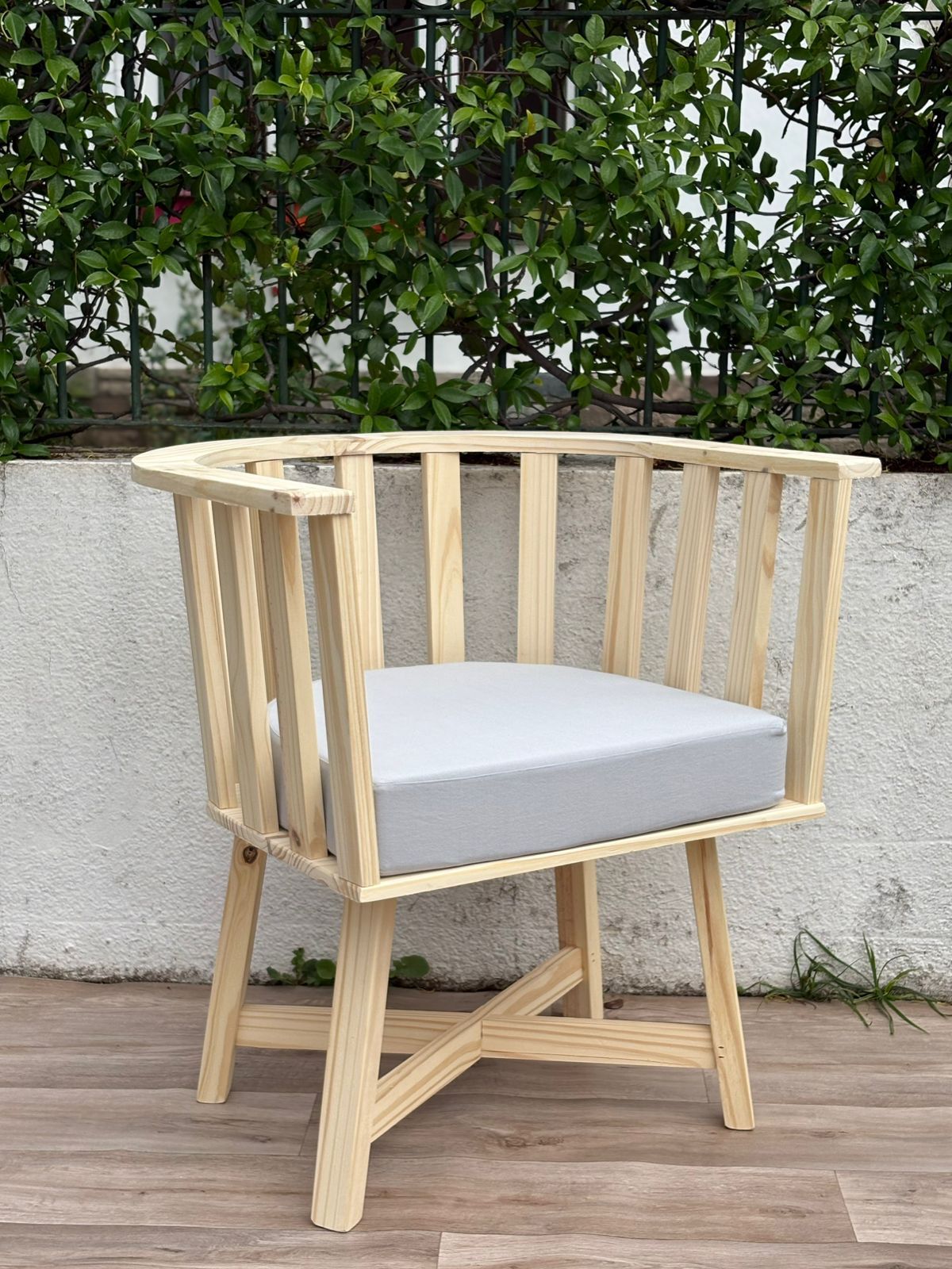 Dos sillas de madera y una pequeña mesa redonda en un patio de ladrillo.