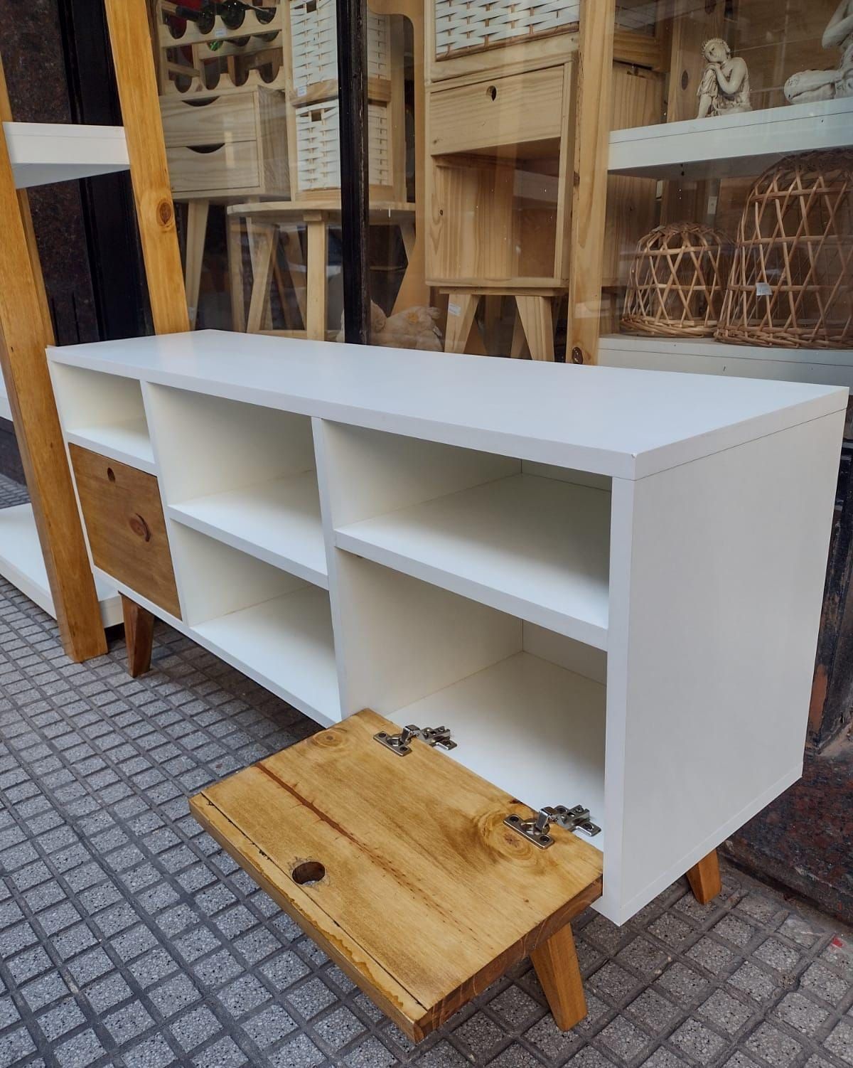 Mueble de TV en color blanco y madera con dos cajones, estantes abiertos y patas en ángulo.