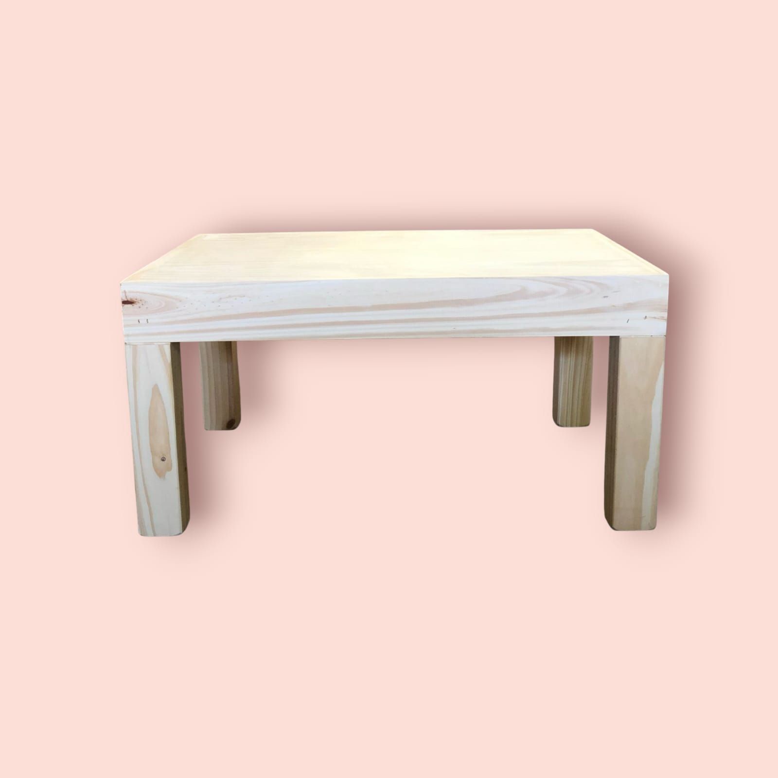 Mesa rectangular de madera con cuatro patas cuadradas, sobre fondo rosa.