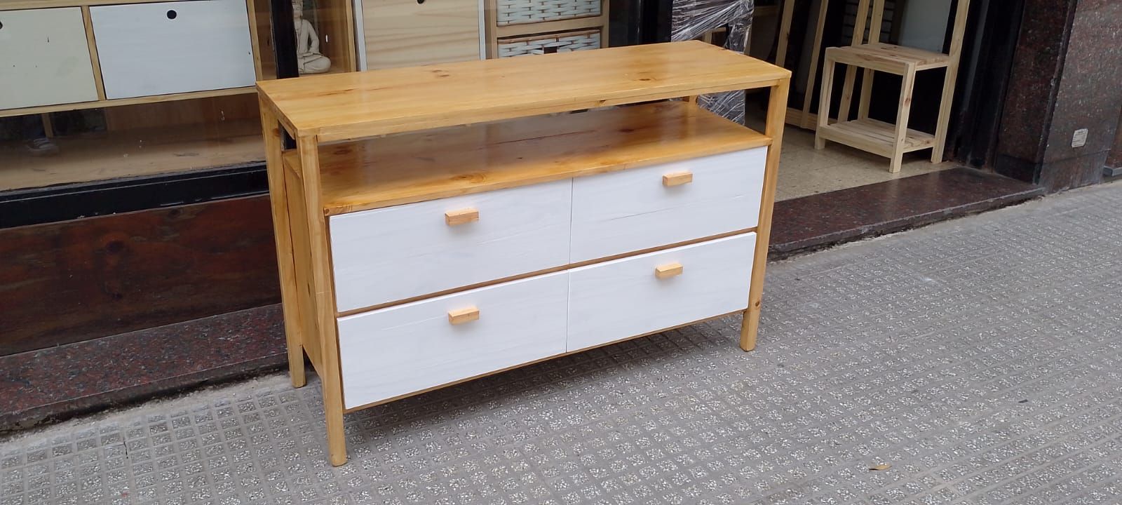 Cómoda de madera con dos cajones blancos y un estante, sobre pasarela de baldosas.