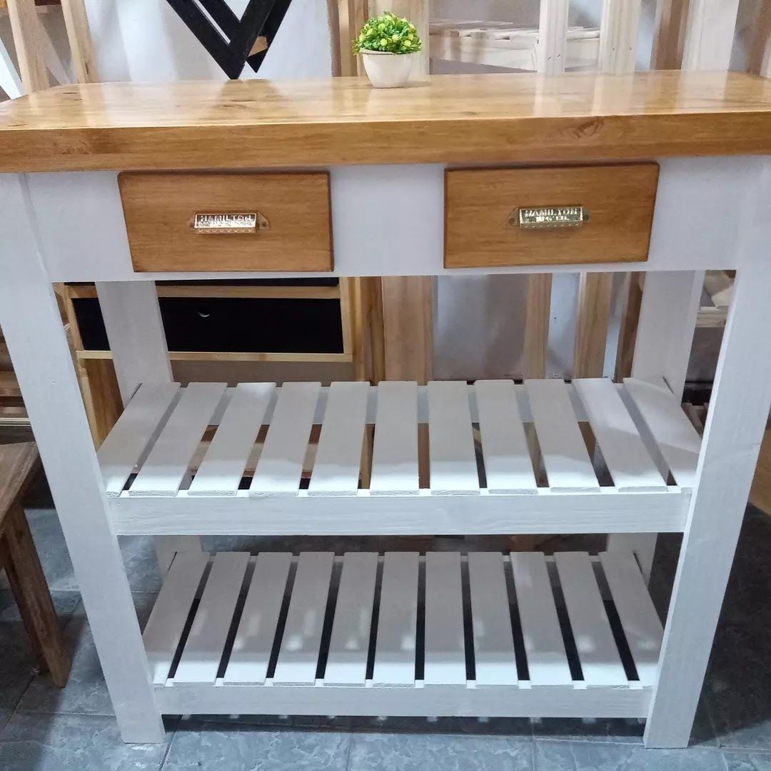 Isla de cocina de madera con estructura blanca, encimera de madera natural, dos cajones y estantes de listones.