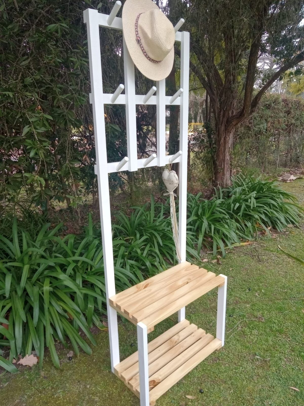 Perchero de madera blanca con banco, sombrero y ganchos para exterior.