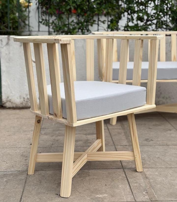 Una silla de madera con un cojín blanco está sobre un suelo de baldosas.