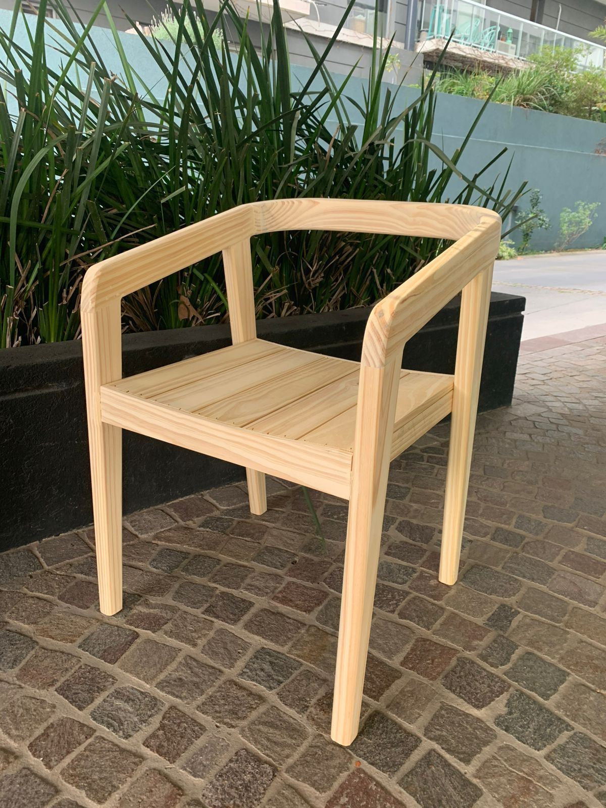 Una silla de madera está sentada sobre una acera de ladrillos.