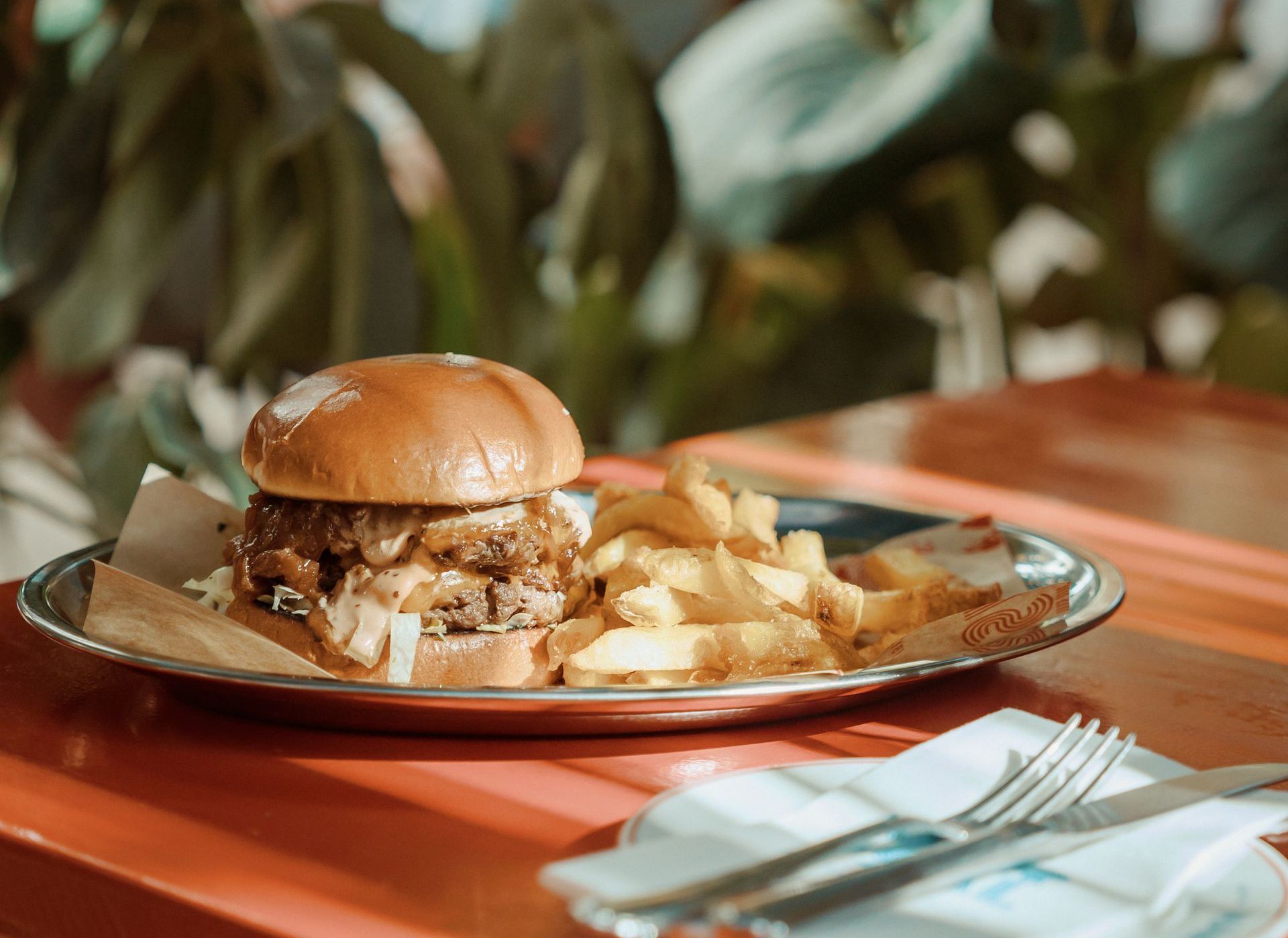 A hamburger and french fries on a plate on a table.