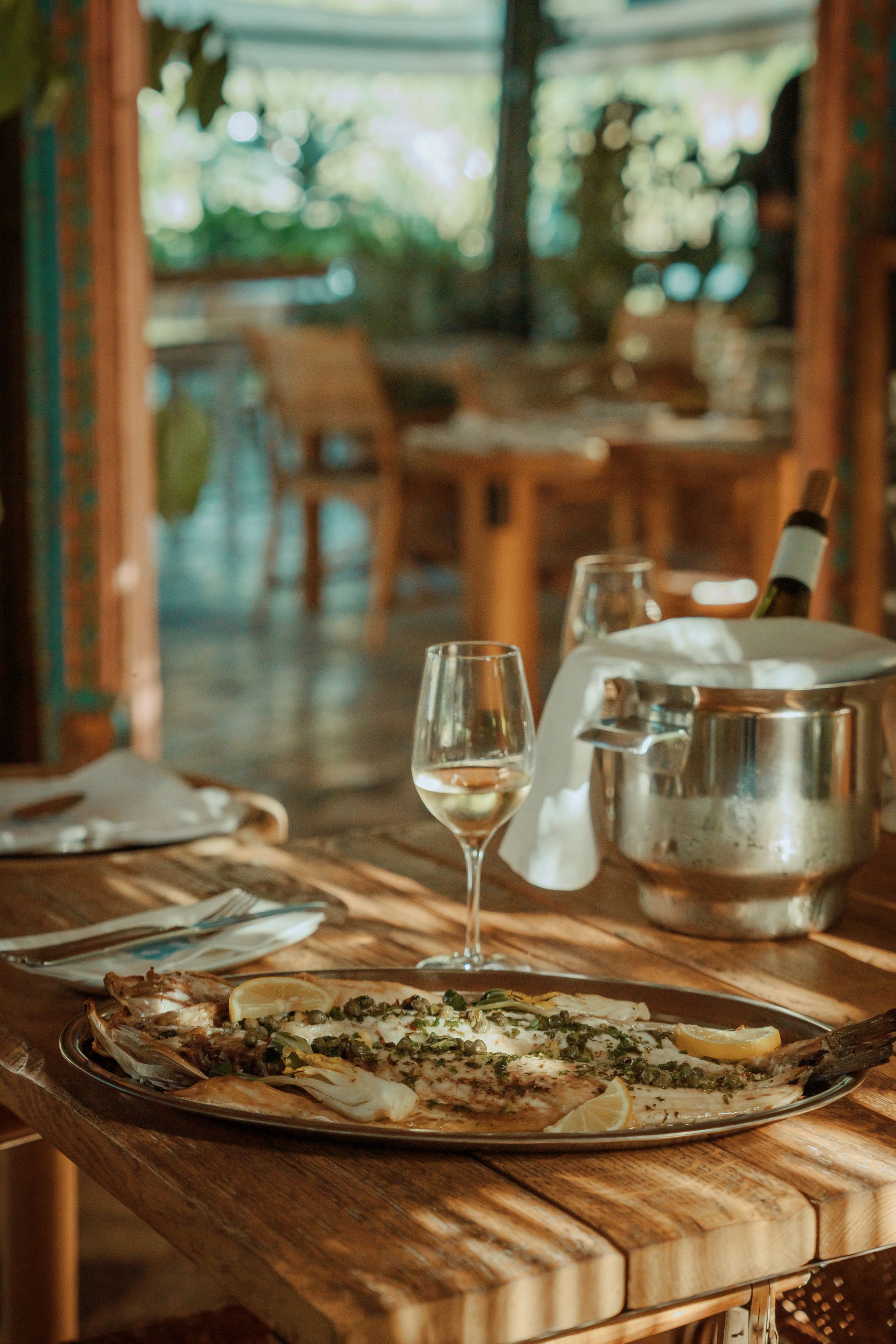 A pizza and a glass of wine are on a wooden table.