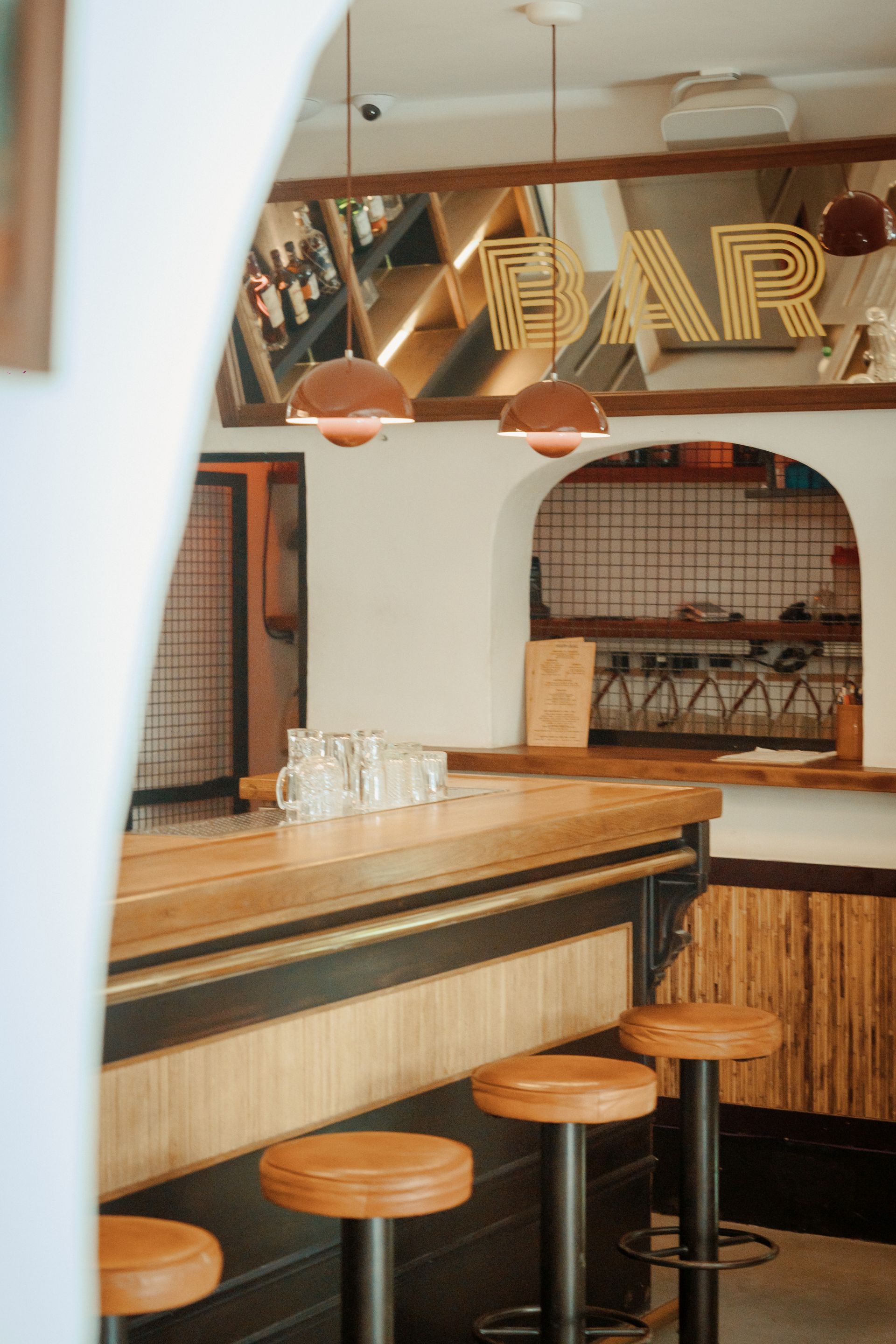 A bar with a wooden counter and stools in a restaurant.