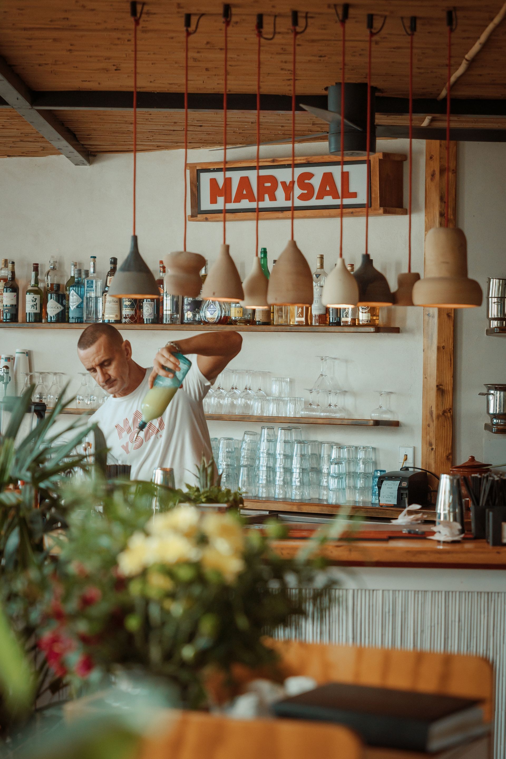 A man is making a drink at a bar in a restaurant.