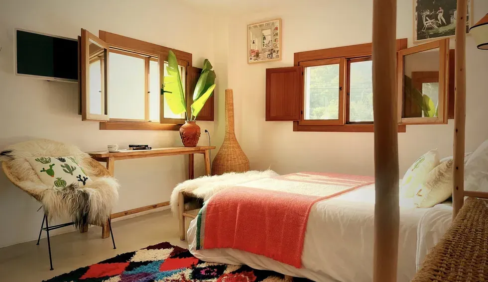 A bedroom with a bed , chair , desk and windows.