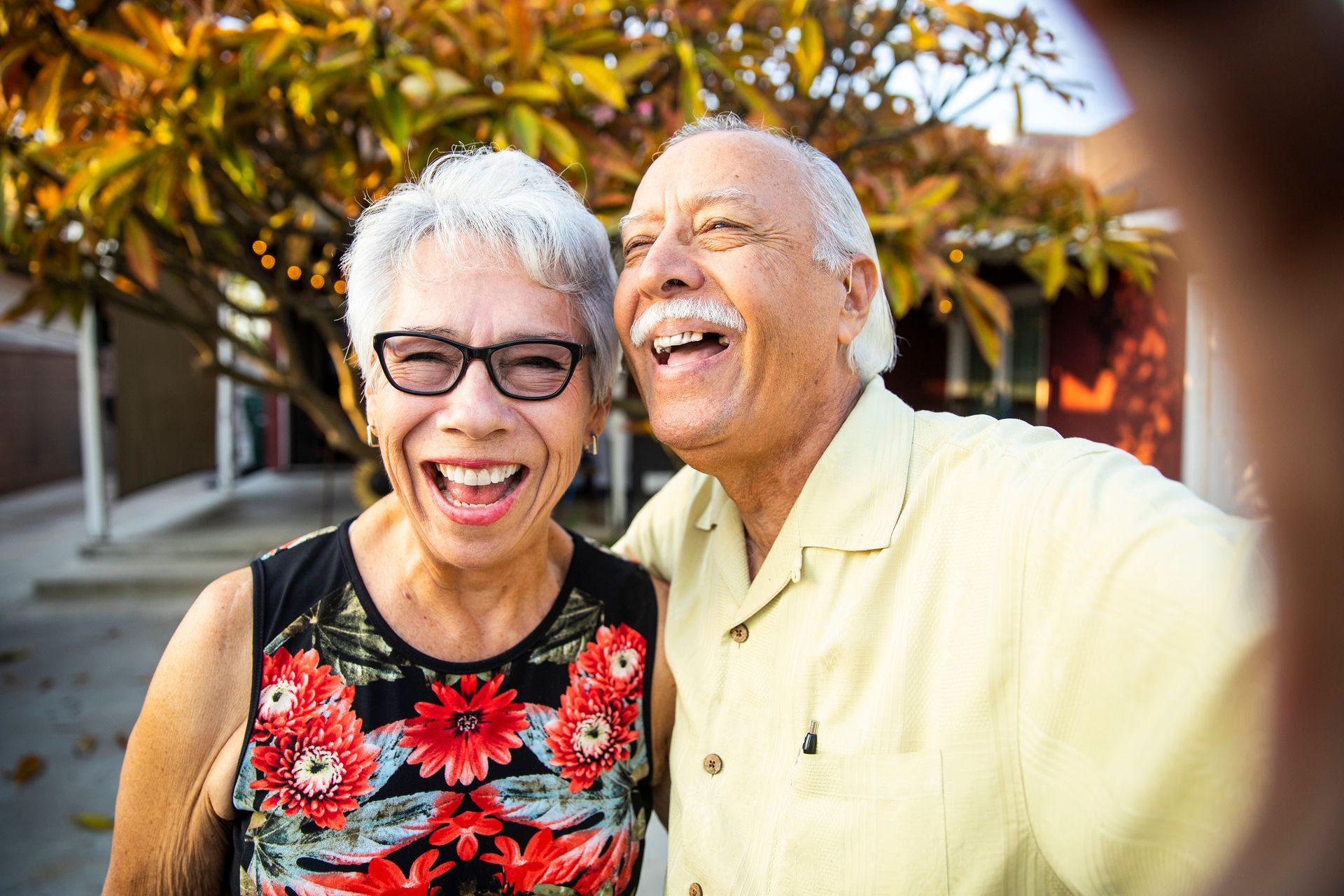 An elderly couple is taking a selfie together and smiling.