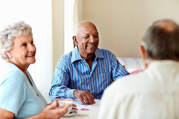 A group of elderly people are sitting at a table playing cards.