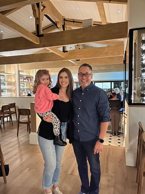 A man and a woman are sitting on a couch holding a baby.