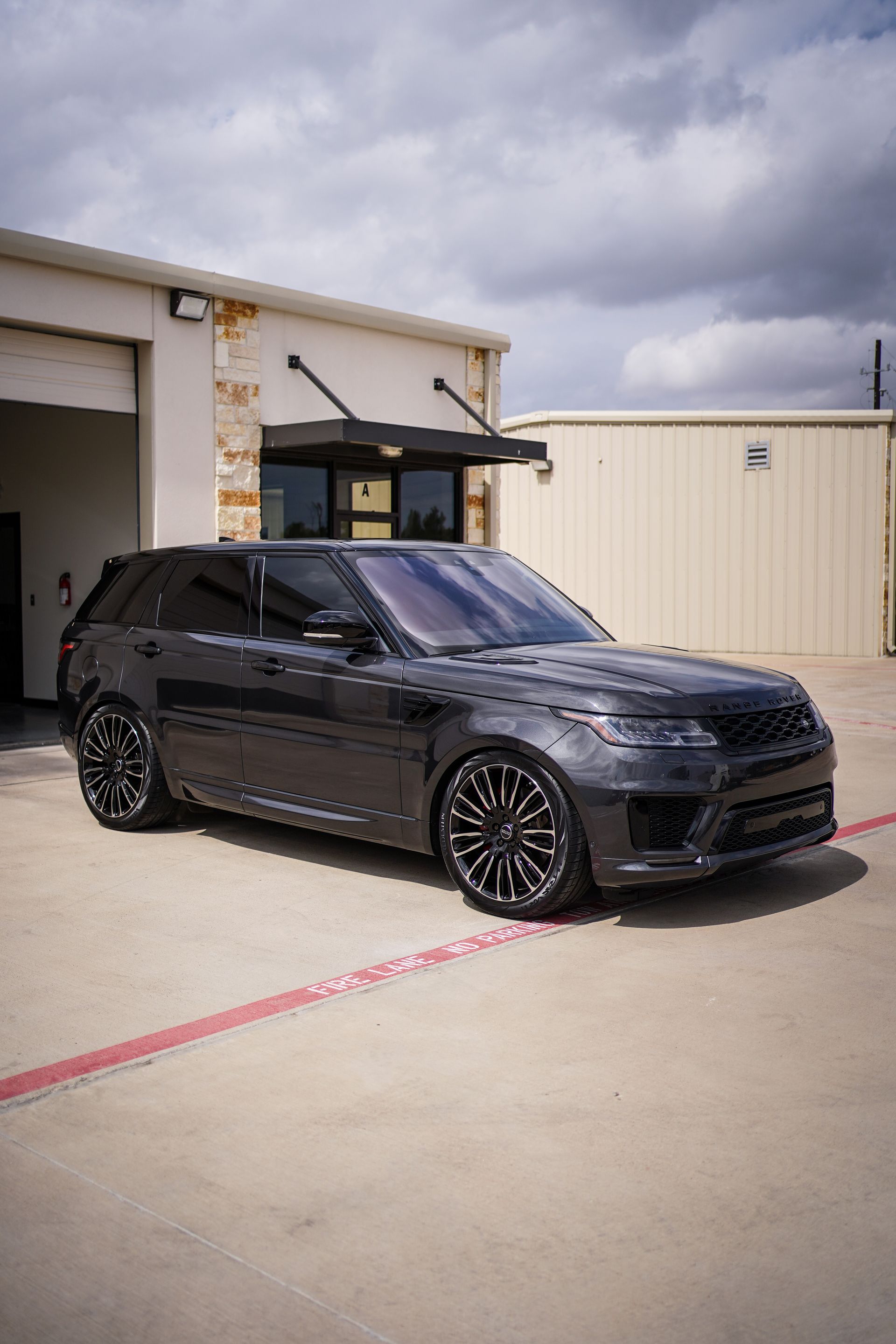 A black range rover sport is parked in front of a building.