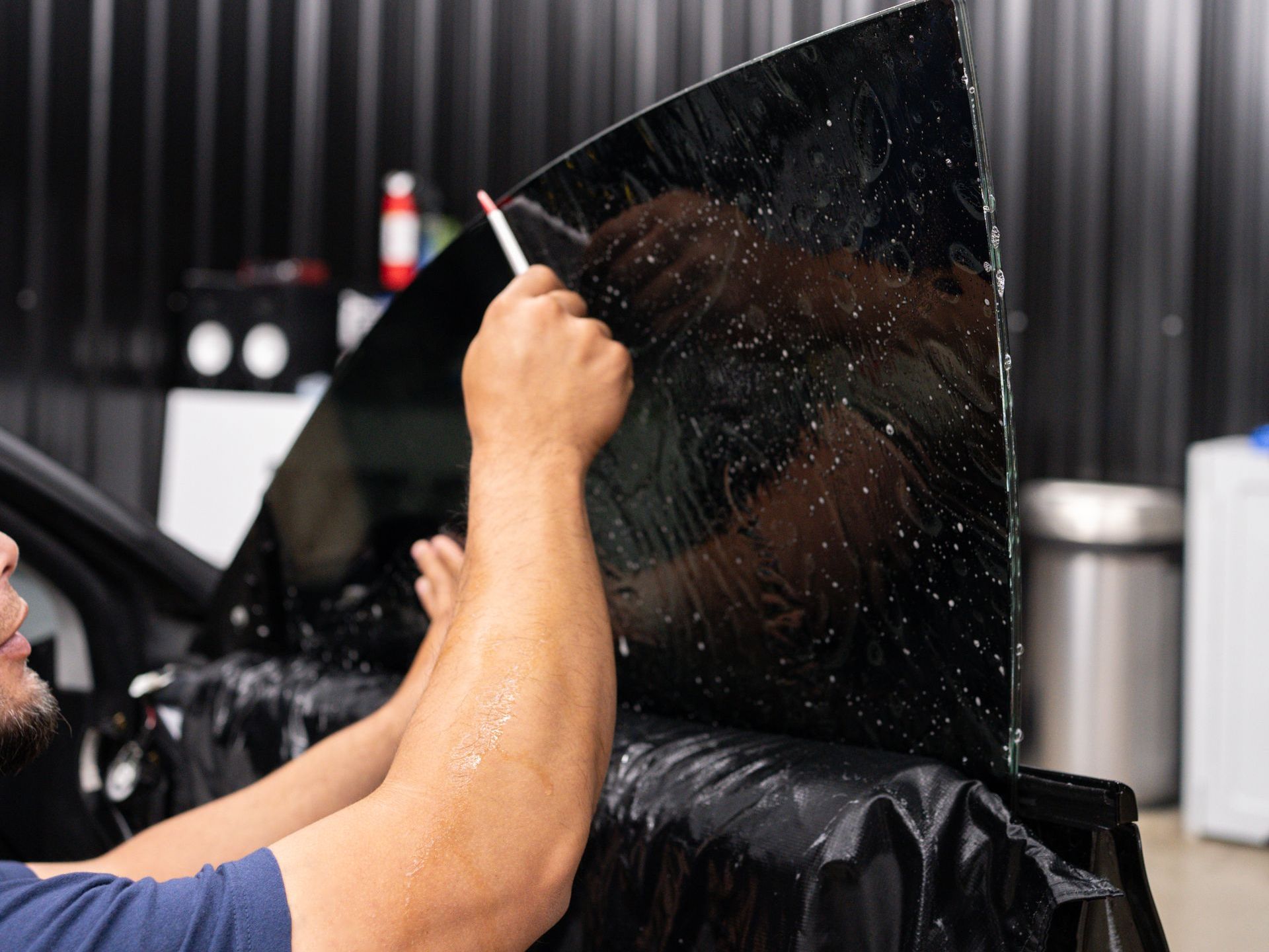 A man is applying window tinting to a car window.