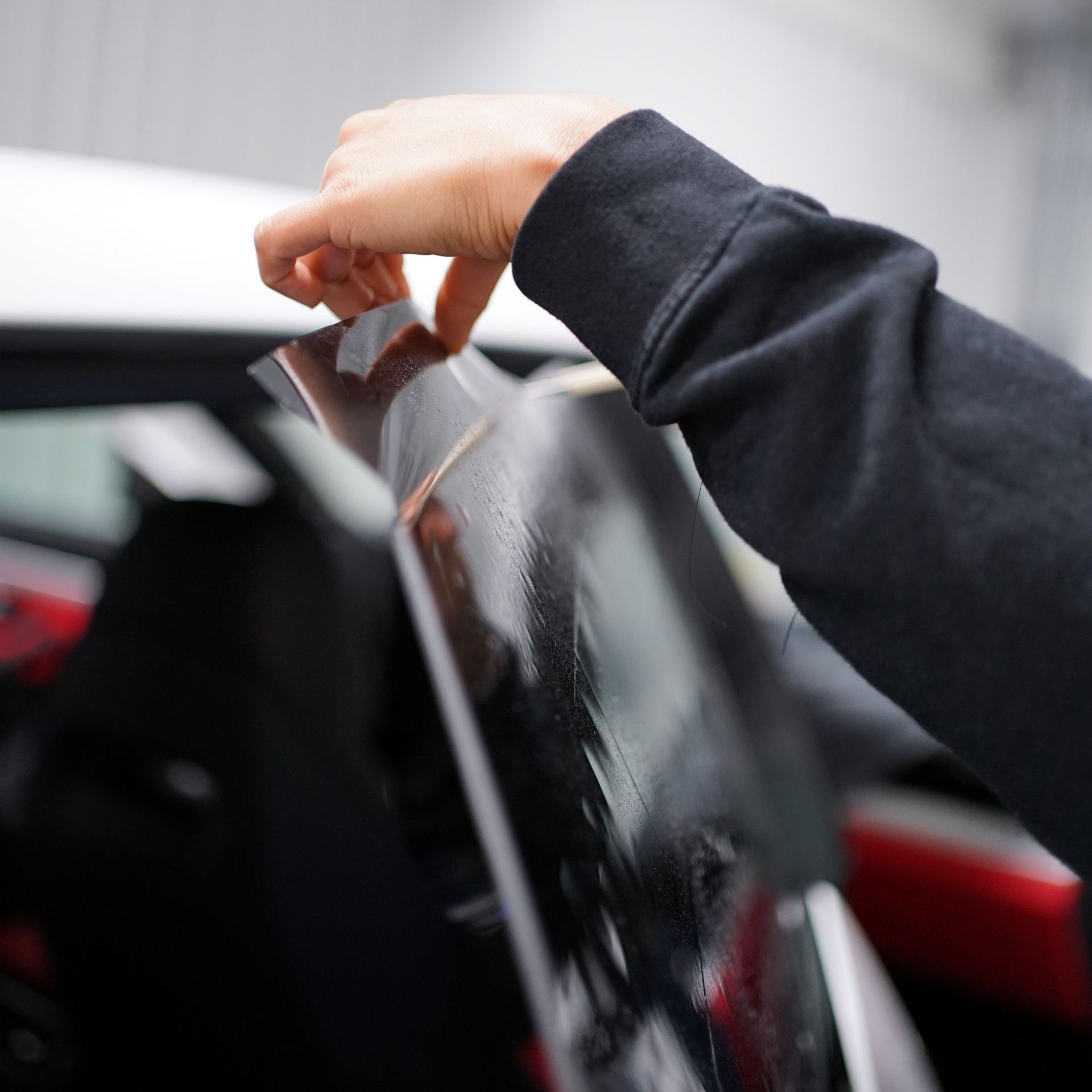 A person is applying tint to a car window