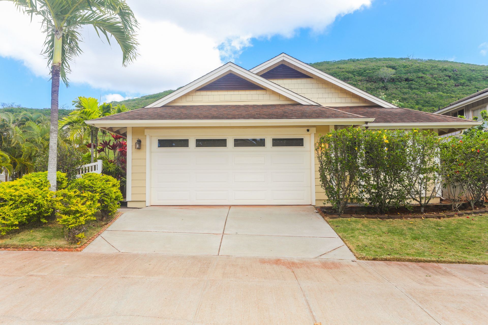 A house with a white garage door and a palm tree in front of it.
