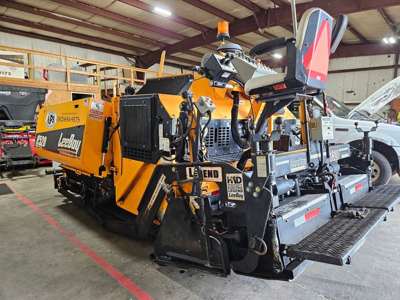 Yellow and black asphalt paving machine inside a building.