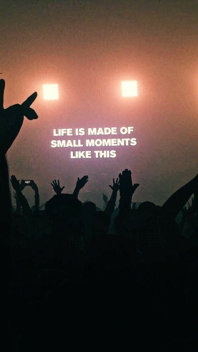 A crowd of people at a concert with a quote on the screen that says `` life is made of small moments like this ''.