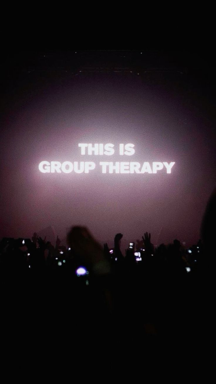 A group of people are standing in front of a sign that says this is group therapy.