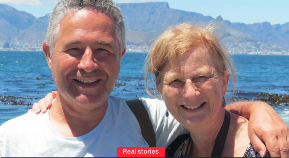 A smiling couple poses for a photo with Table Mountain and the ocean in the background.