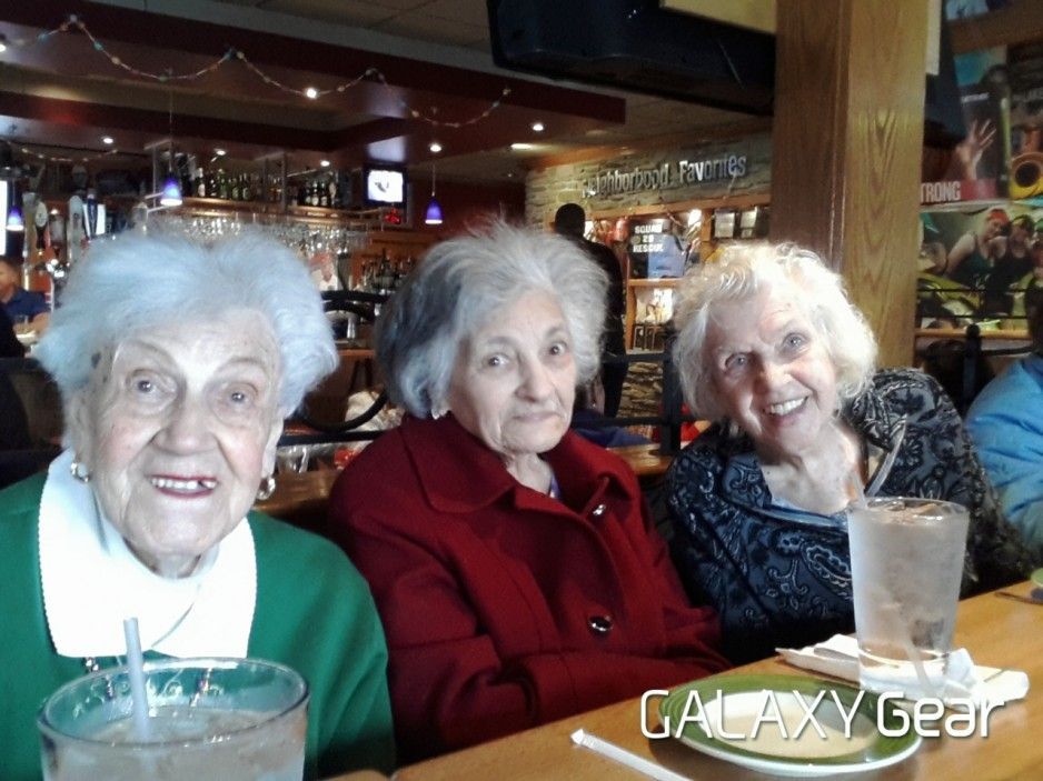Three people smiling at a table in a dimly lit restaurant, each with a glass of water in front of them.
