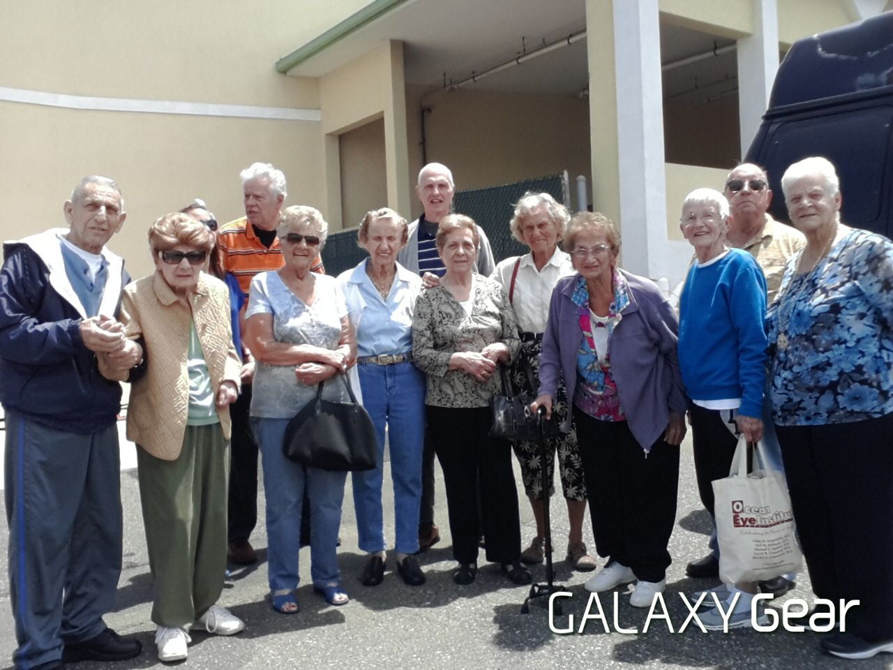 A group of people standing outdoors, smiling and posing for a photo in front of a building.