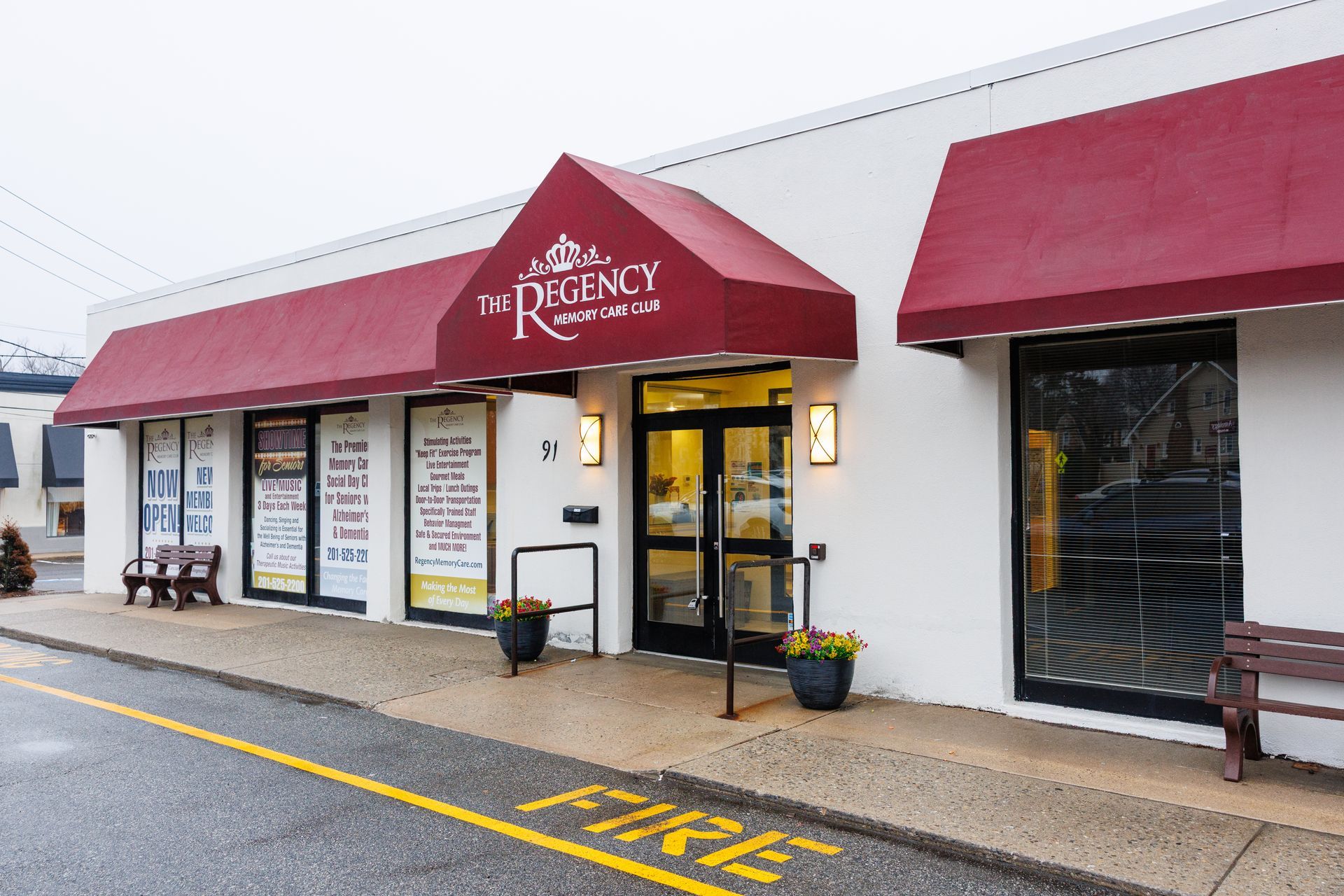 The Regency, a single-story commercial building with white walls and red awnings, sits under a clear blue sky.