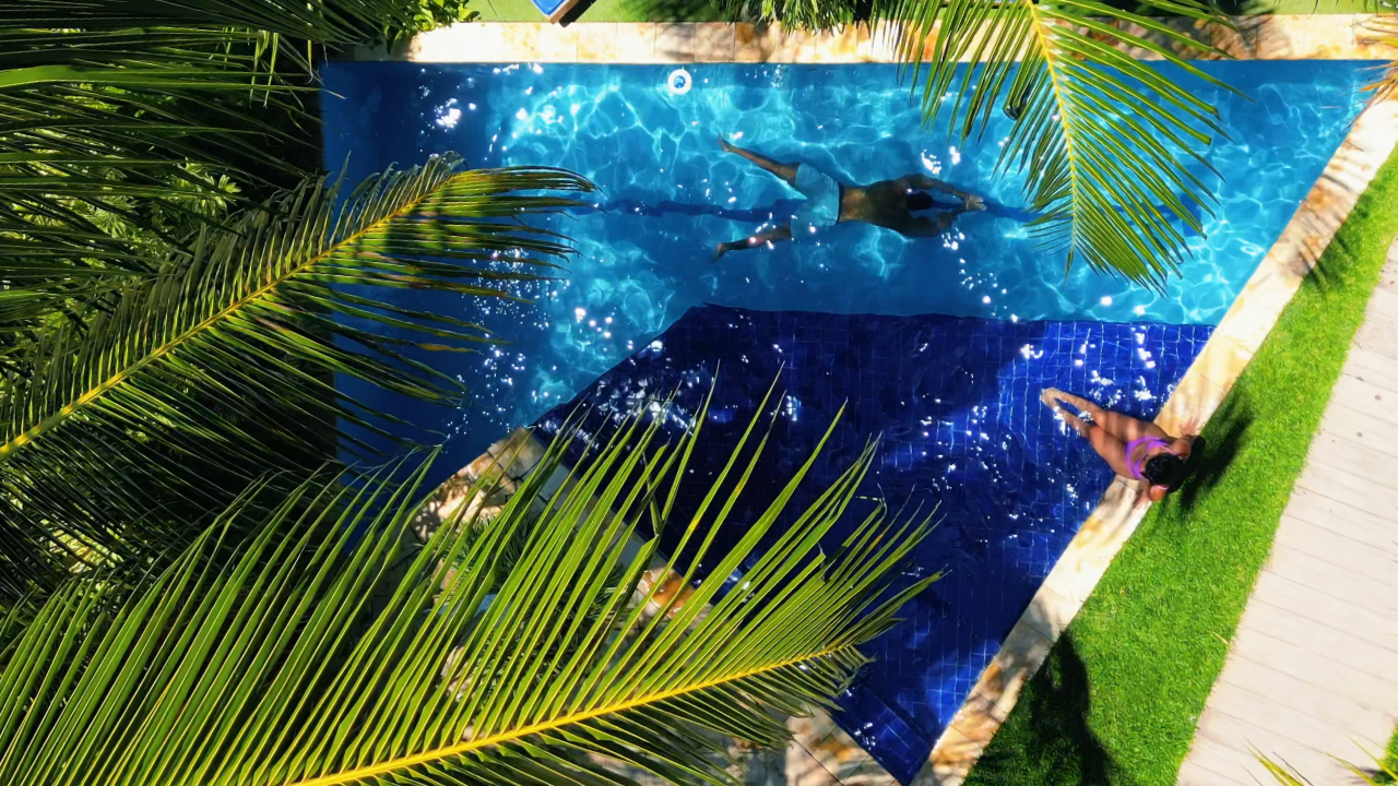 Piscina da Pousada Unaí em Porto de Galinhas, cercada por jardim e área de descanso.