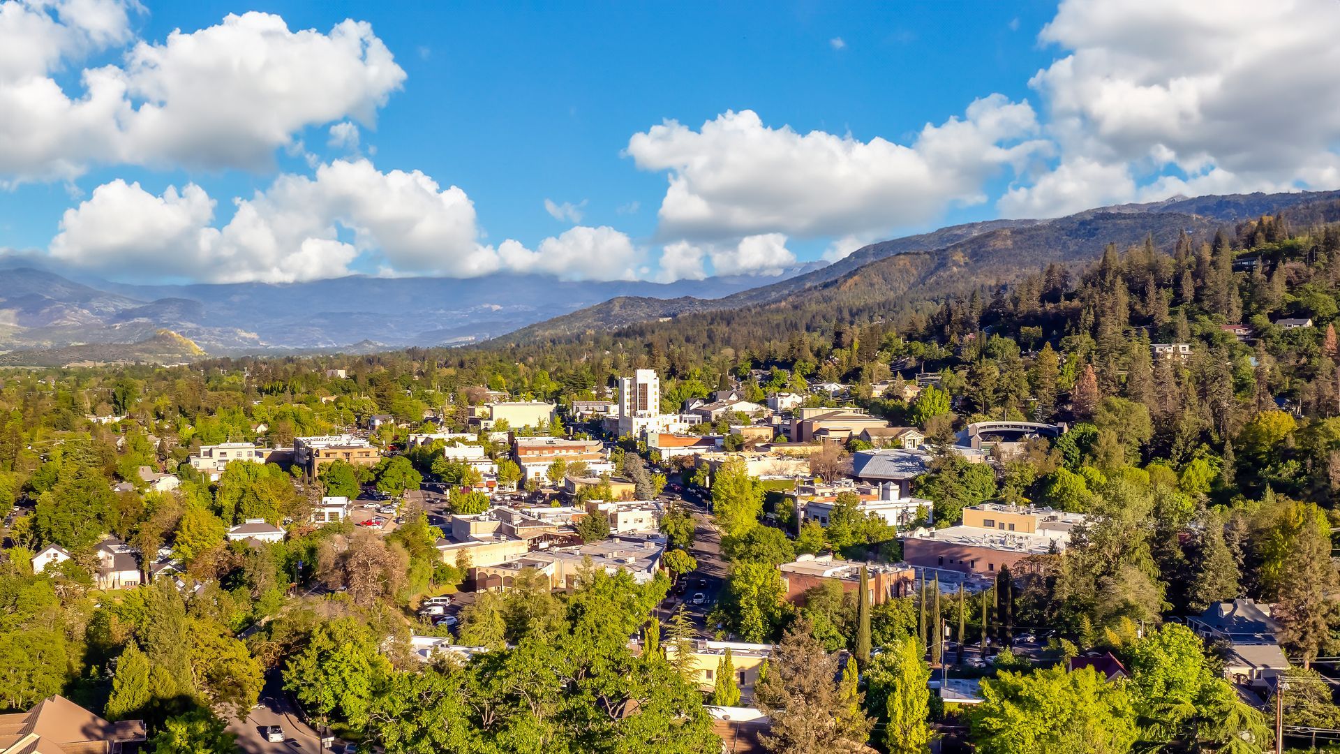 An aerial view of a small town surrounded by trees and mountains.