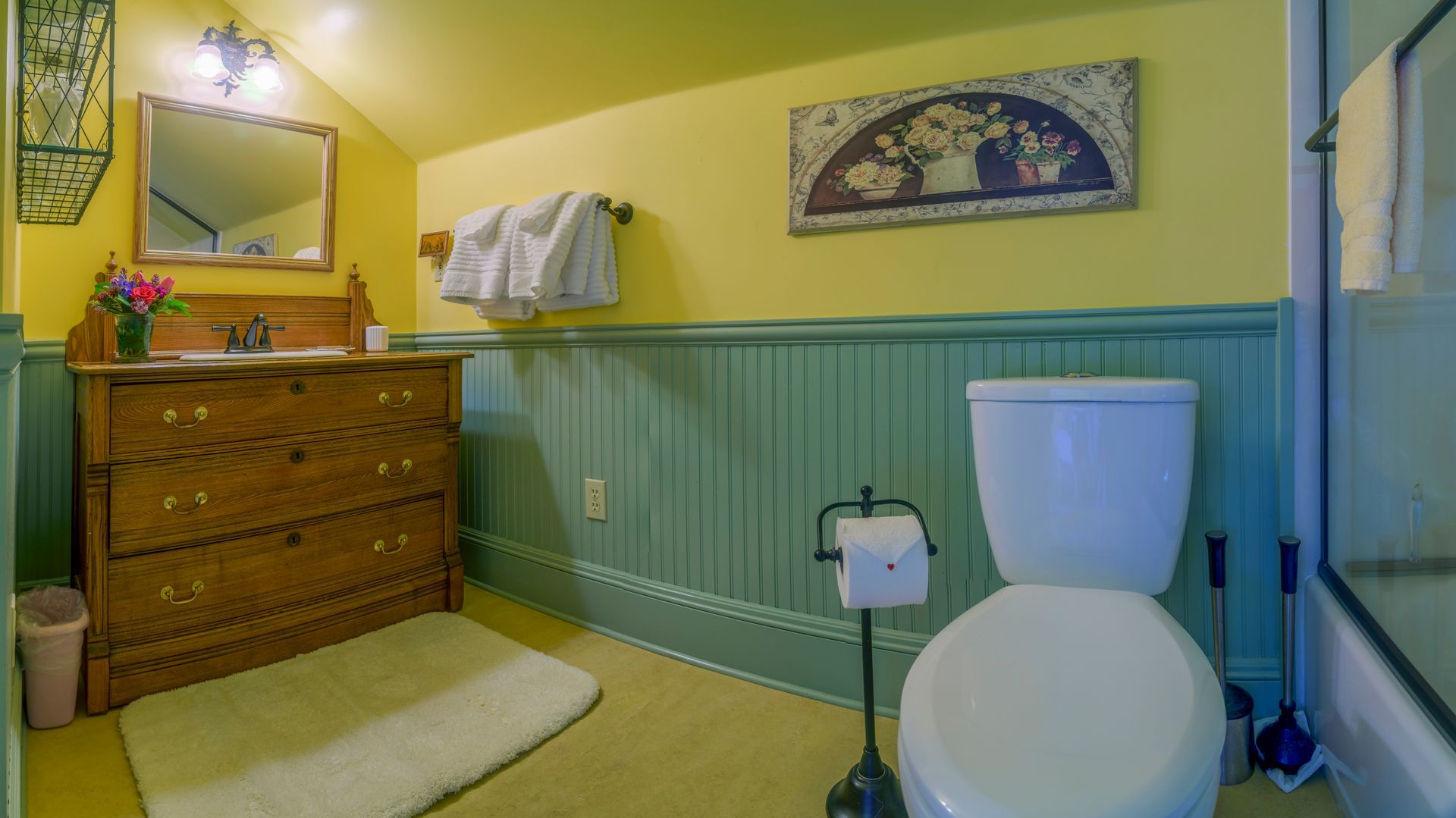 A bathroom with a toilet , sink and mirror.