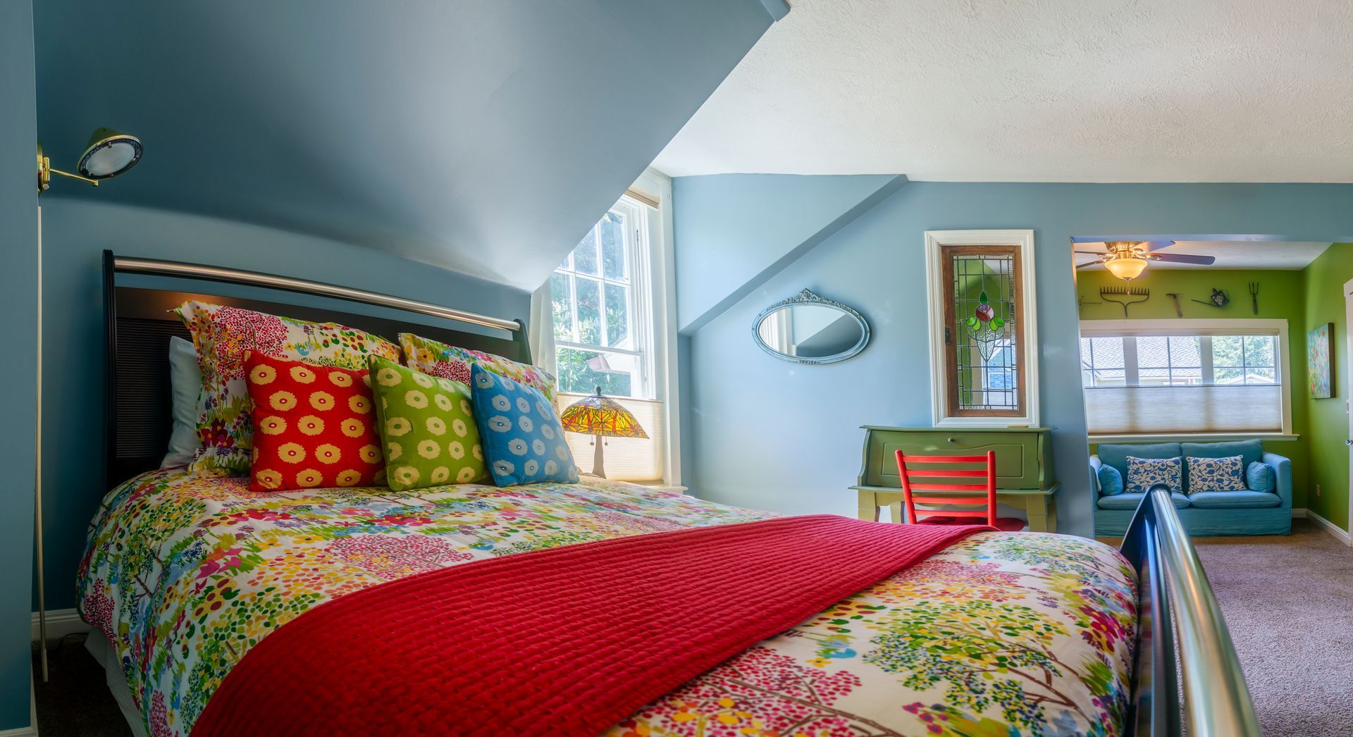 A bedroom with a colorful bed and a red blanket