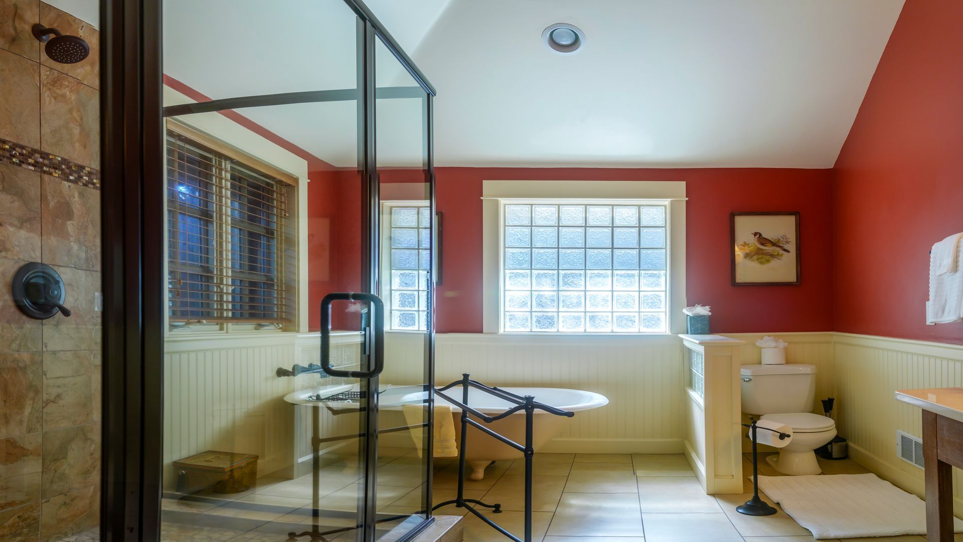 A bathroom with a tub , toilet , shower and window.