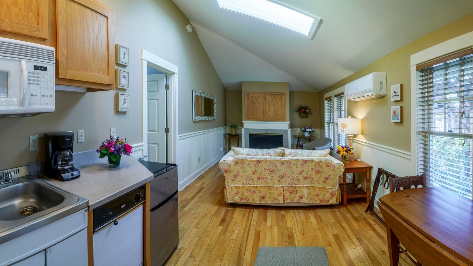 A living room with hardwood floors , a couch , a table and a microwave.