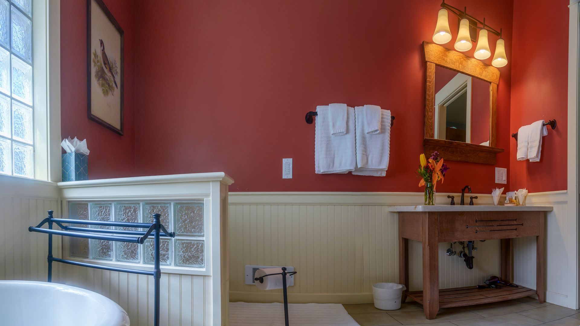 A bathroom with red walls , a sink , and a bathtub.