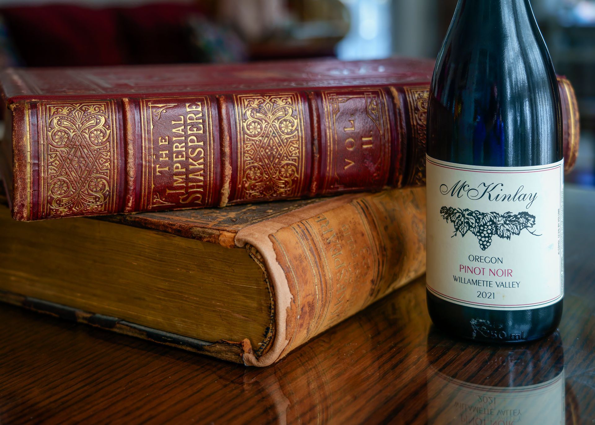 A bottle of wine is sitting next to a stack of books.