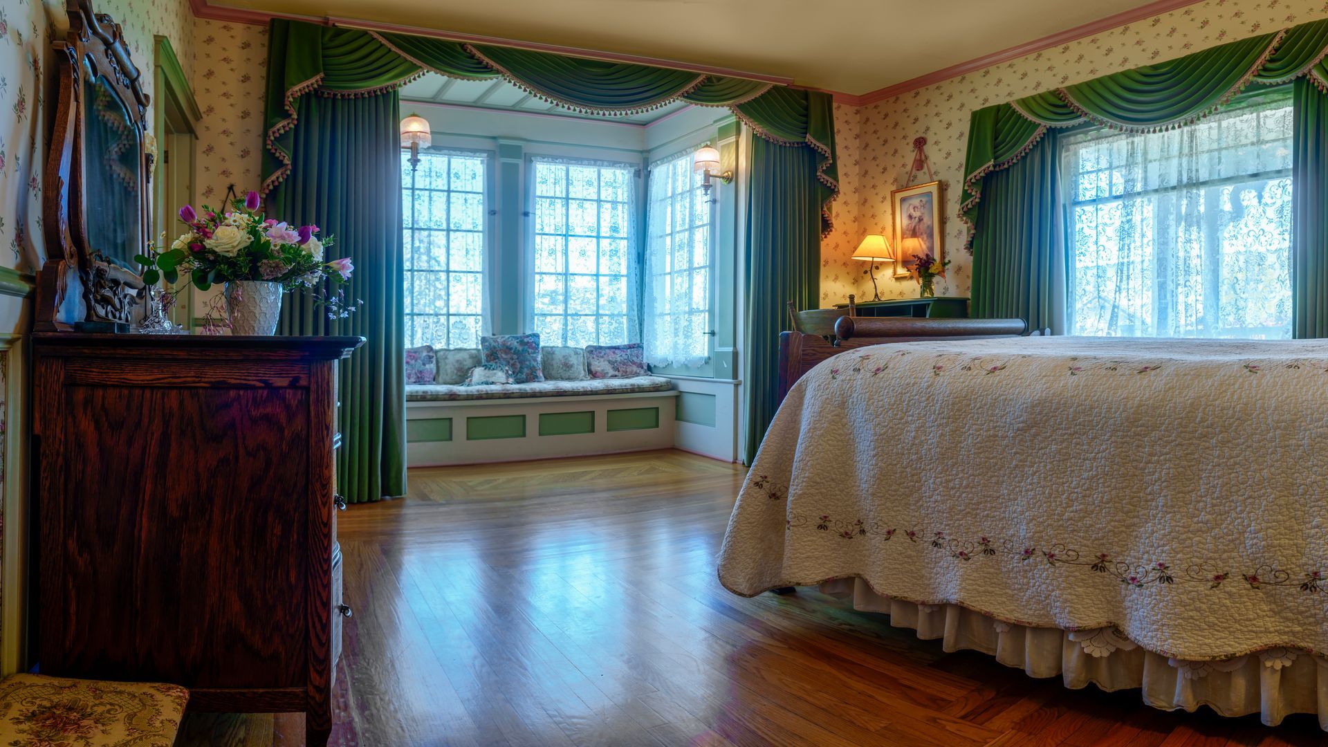 A bedroom with a large bed , dresser , and window seat.