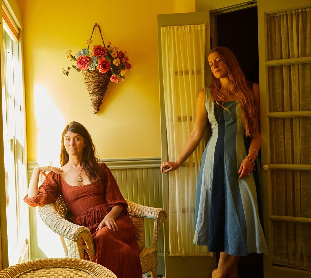 A woman in a red dress sits in a chair next to a woman in a blue dress