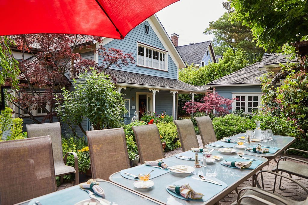 A patio table with plates and umbrellas in front of a house.