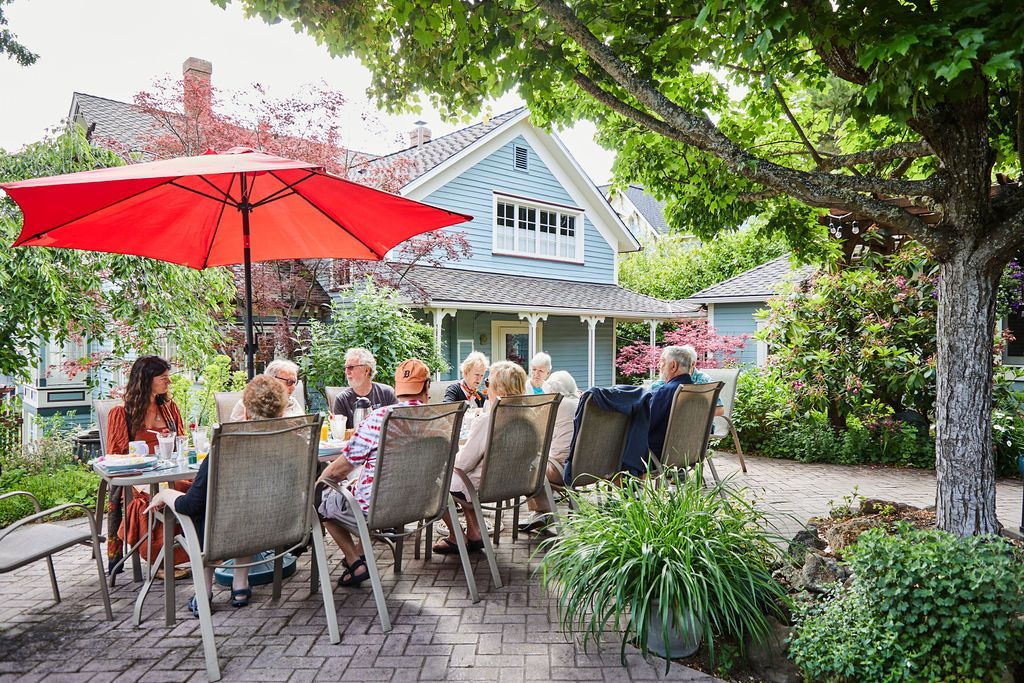 A group of people are sitting at a table under an umbrella.