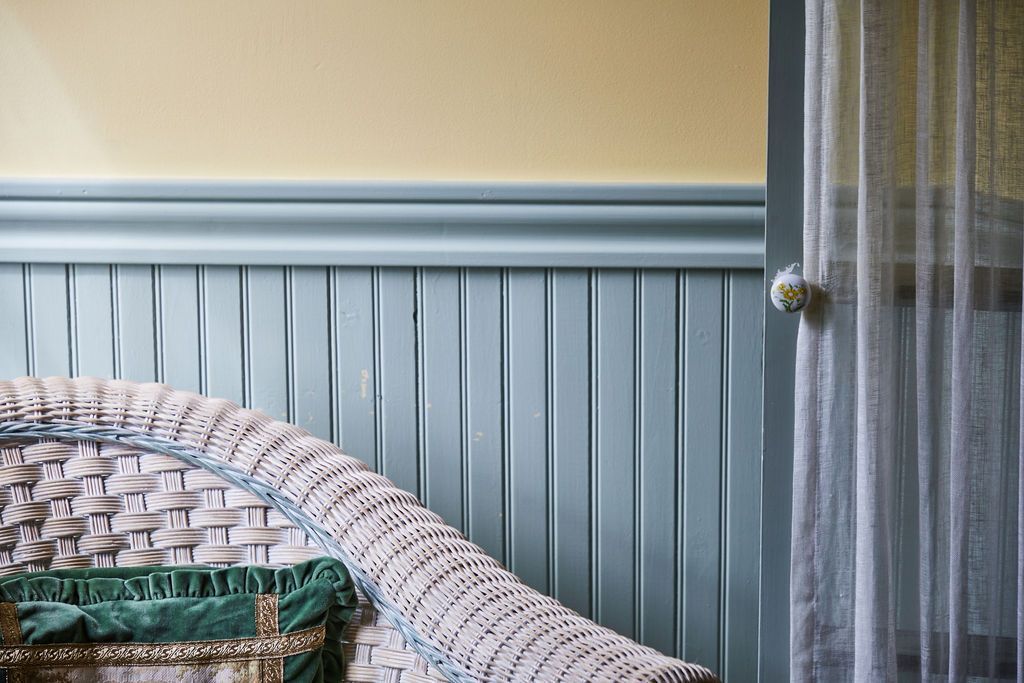 A wicker chair is sitting in a room next to a window.