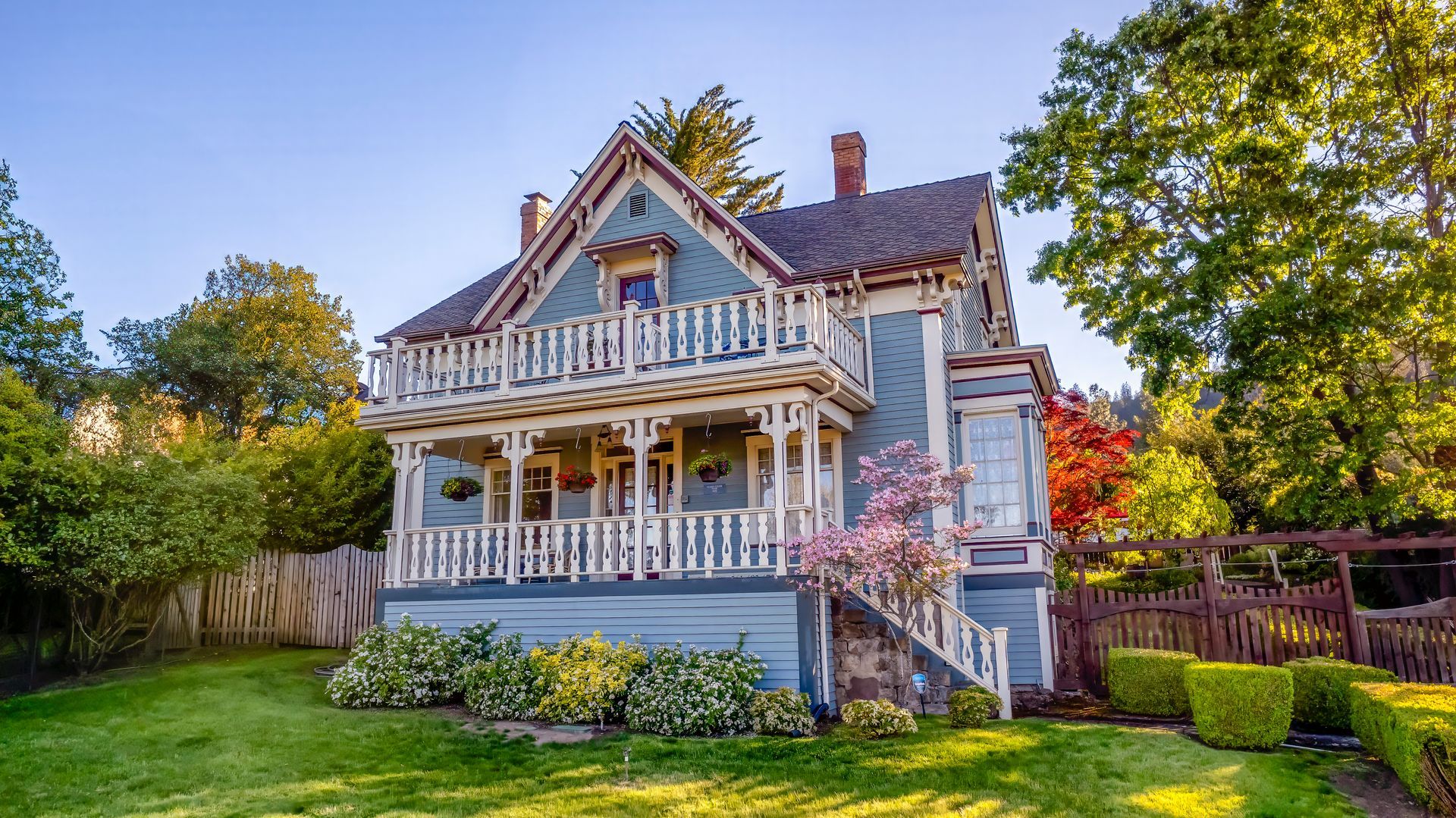 A large house with a large porch is sitting on top of a lush green lawn.