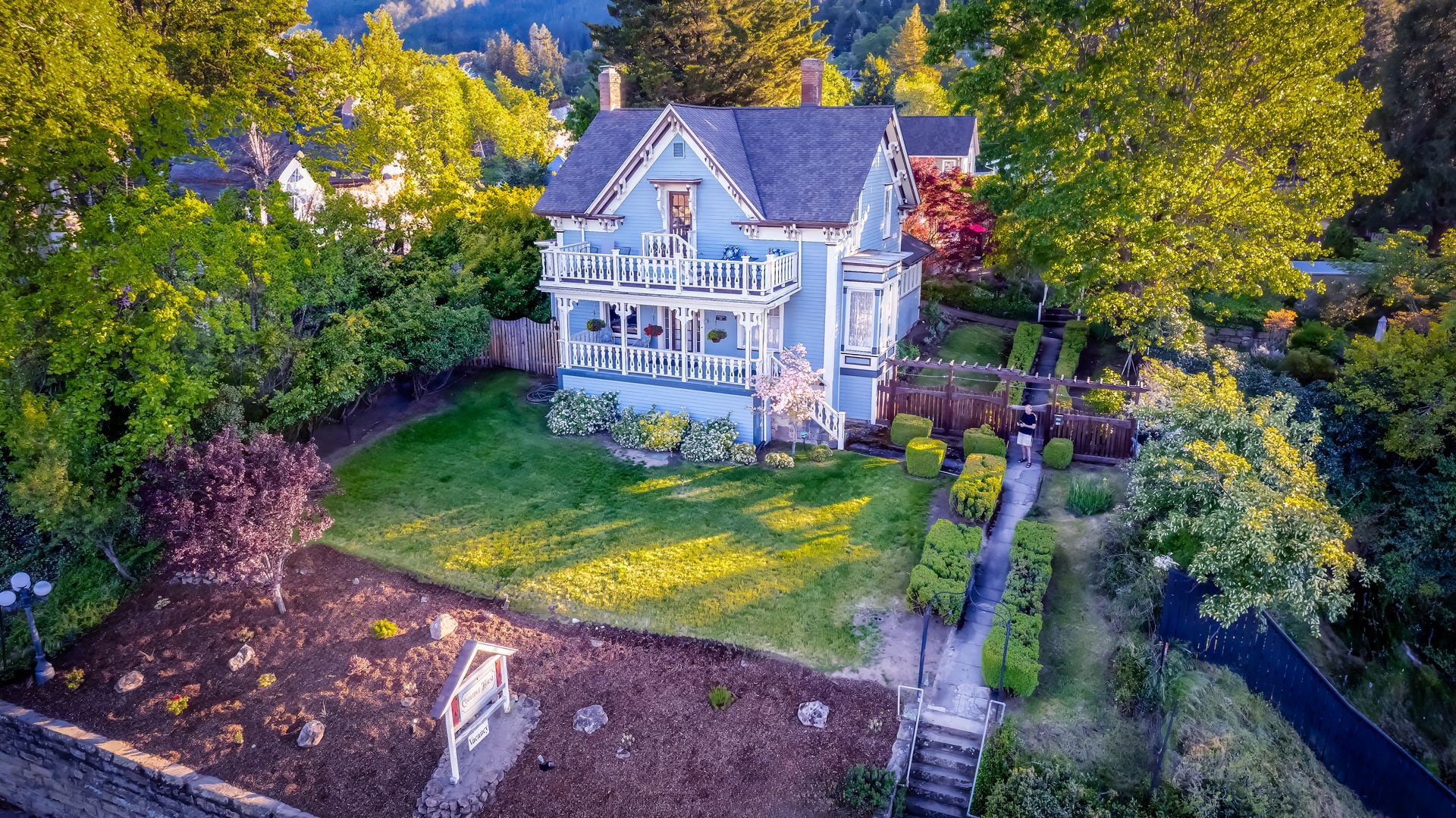 An aerial view of a large blue house surrounded by trees.