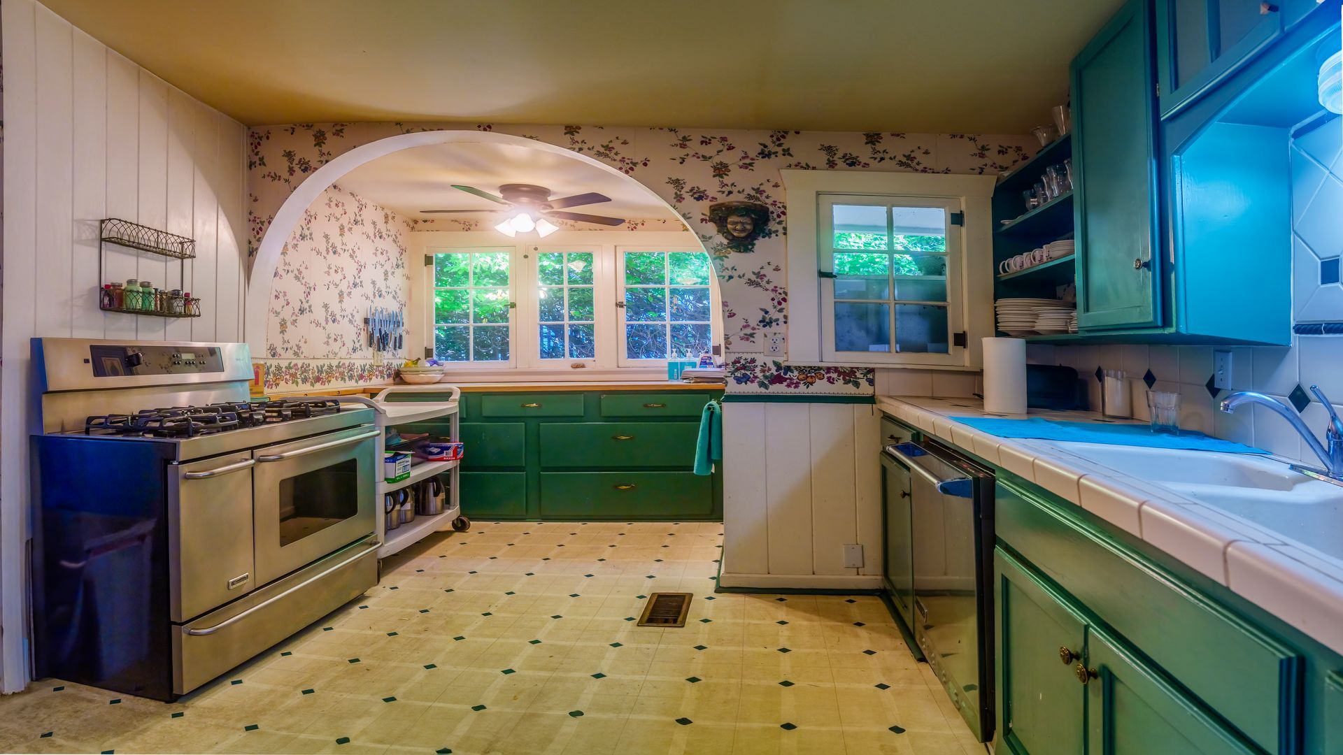 A kitchen with green cabinets , a stove and a sink.