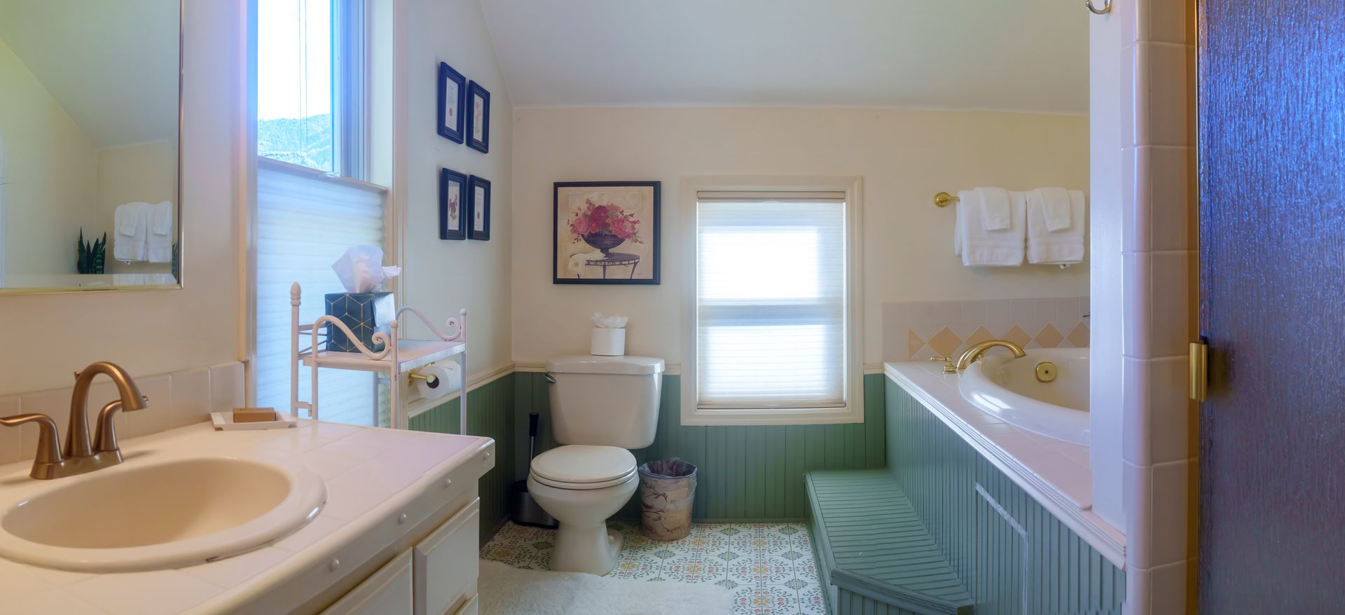 A bathroom with a sink , toilet , tub and window.