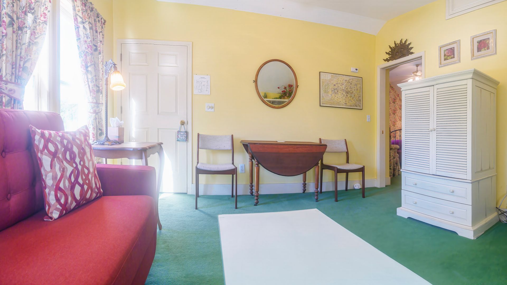 A living room with a red couch , table and chairs.