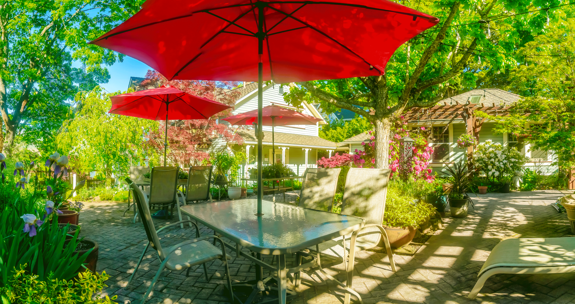 A patio with a table and chairs under red umbrellas.